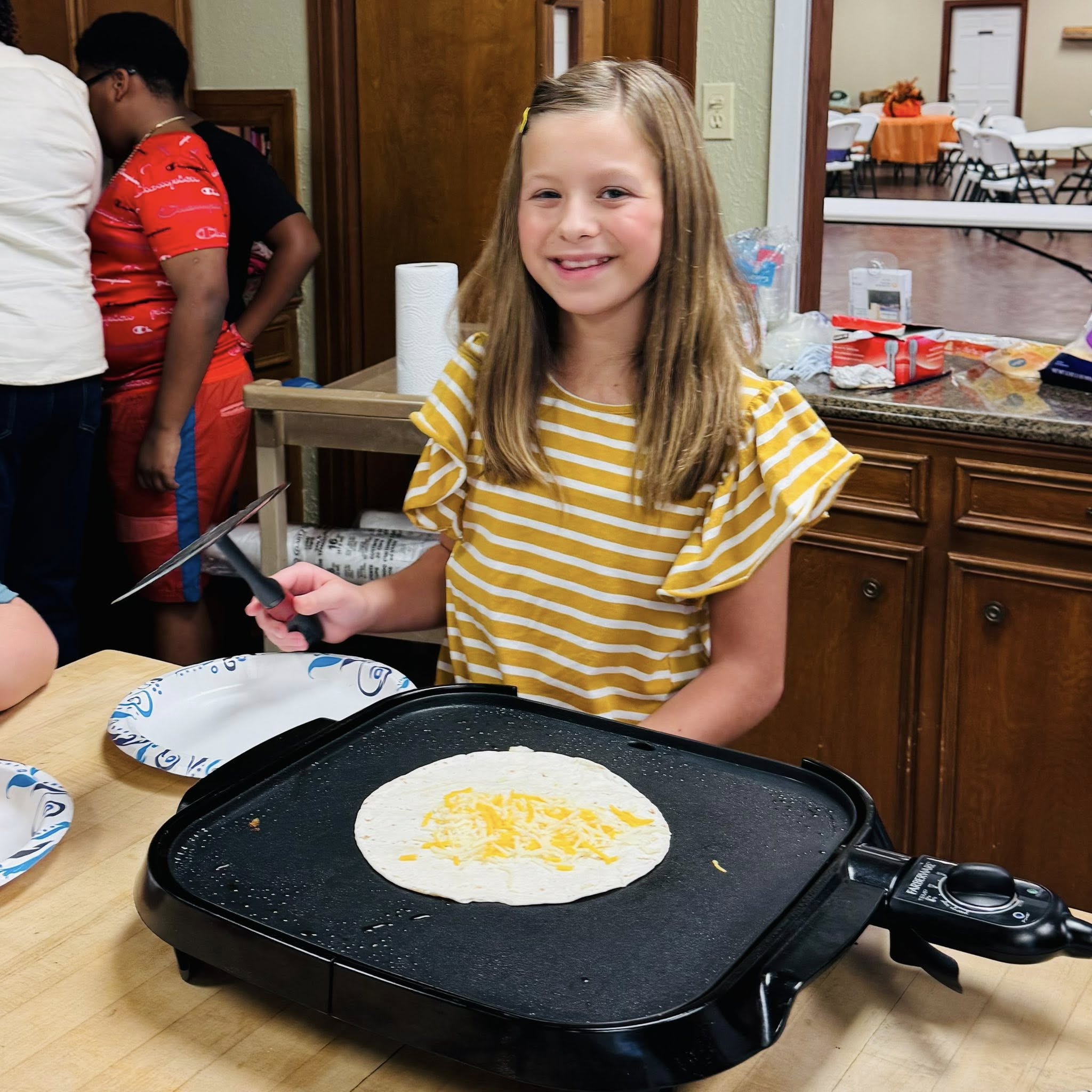 A girl cooking on a griddle.